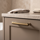 Veyra solid brass small cabinet pull installed on a warm taupe luxury bathroom vanity